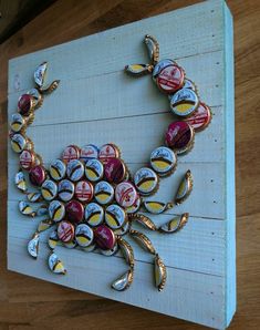 a crab made out of beer bottle caps on a wooden board with gold trimmings