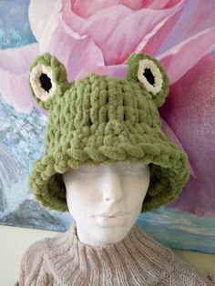 a crocheted frog hat on top of a mannequin's head