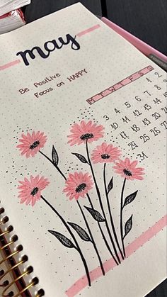 a planner with pink flowers on it next to a cup of coffee and a pen