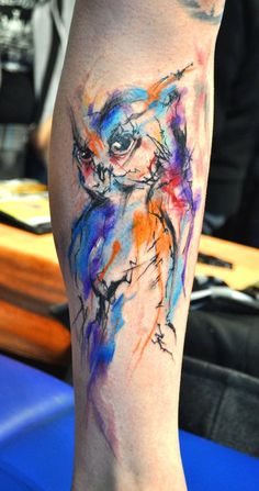 a colorful owl tattoo on the leg