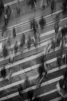 an overhead view of people walking across a crosswalk in black and white, taken from above