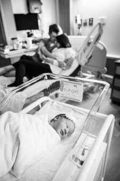 a baby laying in a hospital bed next to two adults