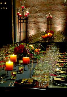 a long table is set with wine glasses, candles and plates for an elegant dinner