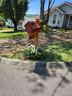 a mailbox in the middle of a flower bed with flowers growing out of it