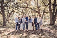 a group of people standing next to each other in front of some trees and leaves