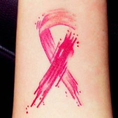 a pink ribbon tattoo on the wrist