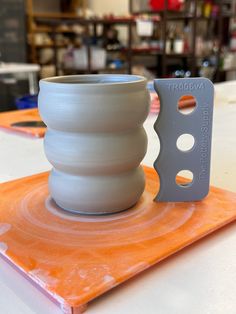 a white vase sitting on top of an orange plate