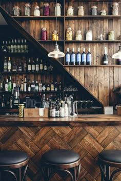 a bar with stools and shelves filled with bottles