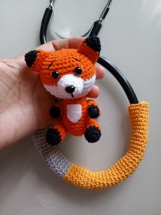 a hand holding a crocheted keychain shaped like a fox