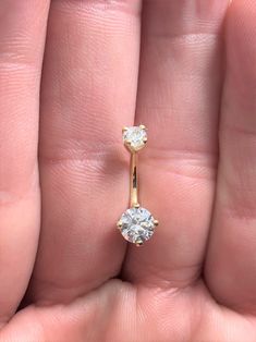 a close up of a person's hand holding a ring with two diamonds on it