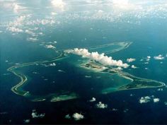 an island in the ocean surrounded by clouds