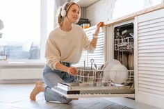 a woman is sitting in front of the dishwasher