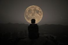 a person sitting on top of a rock looking at the moon