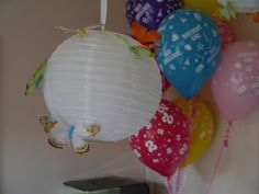 a bunch of balloons that are hanging from the ceiling and some butterflies on one of them