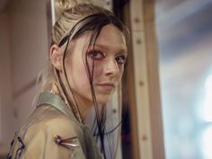 a woman with long hair and piercings standing next to a wall in a room