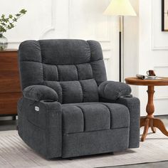 a grey recliner sitting on top of a rug in a living room next to a table