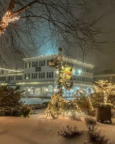 a large white building with christmas lights on it's sides and trees in the foreground