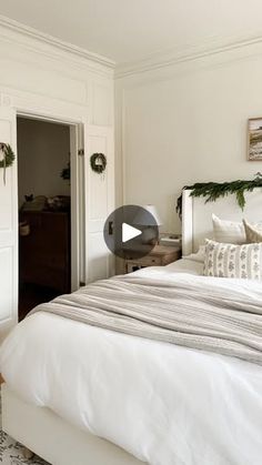 a bed with white sheets and pillows in a bedroom next to a closet filled with christmas wreaths