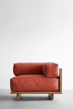 a red couch sitting on top of a wooden frame in front of a white wall