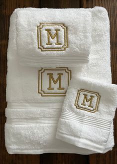 three white towels with gold monogramming on them