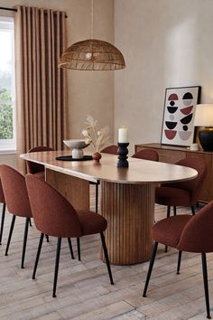 a dining room table with chairs and a vase on the end, in front of a window