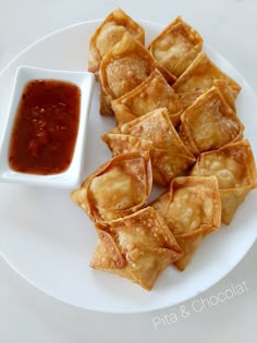 some food is sitting on a white plate with dipping sauce in the bowl next to it