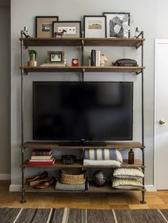 a flat screen tv sitting on top of a wooden shelf next to a wall mounted television