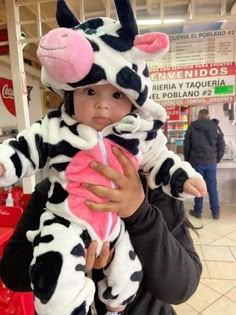 a woman holding a child wearing a cow costume