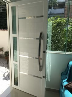 a white door with glass panels in front of a window and blue chair next to it