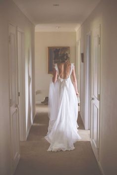 the back of a bride's dress as she walks down a hallway in her wedding gown