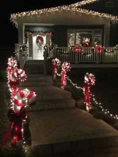 christmas lights are on the front steps of a house with wreaths and bows around them