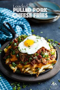 loaded pulled pork cheese fries on a black plate with a fork and blue checkered napkin