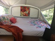 a bed in a tent with pillows and blankets on the bedspread next to it