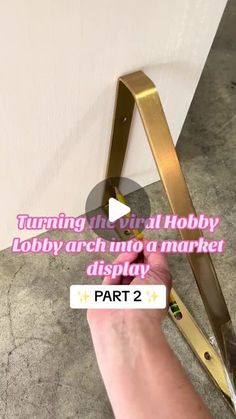 a person is cutting metal with scissors on the floor next to a white wall and text that reads, turning the girl hobby lobby arch into a market display display part 2