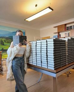 a woman standing in front of stacks of binders and holding up a large book