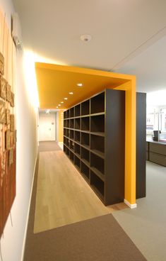 an empty library with yellow walls and black bookshelves on either side of the room