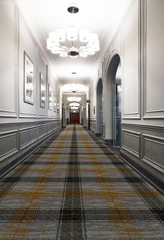 an empty hallway with carpeted floors and framed pictures on the walls