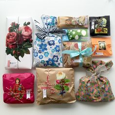 many wrapped presents are displayed on a white surface with ribbons and tags attached to them