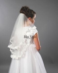 the back of a bride's wedding dress, with her veil draped over her shoulder