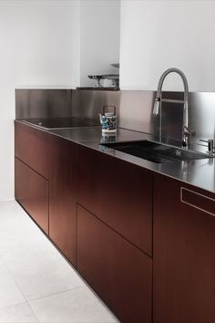 a kitchen with stainless steel counter tops and wooden cabinetry, along with a sink