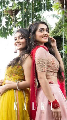 two women standing next to each other in front of a tree with the words kalk written on it