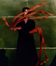 a woman in a black dress is holding red ribbons