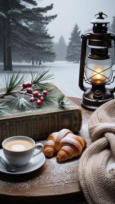 a cup of coffee and some croissants are on a table in the snow