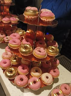 there are many pink and gold cupcakes on the table together with other pastries