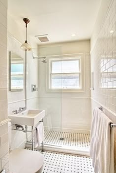 a white bathroom with black and white floor tiles on the shower, sink, and toilet