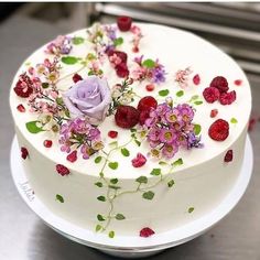 a white cake with flowers and berries on it