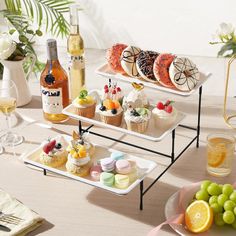 three tiered trays filled with cupcakes, fruit and wine on top of a table