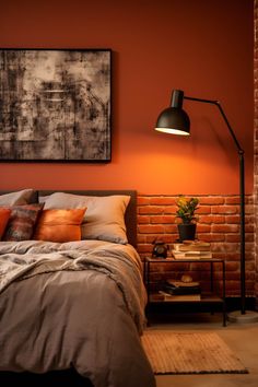 a bedroom with an orange brick wall and a large painting on the wall above the bed