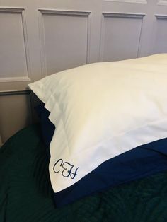 a white and blue pillow sitting on top of a bed next to a green blanket