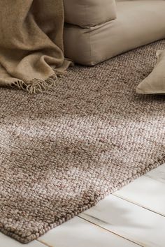 a close up of a rug on the floor with pillows and blankets in the background